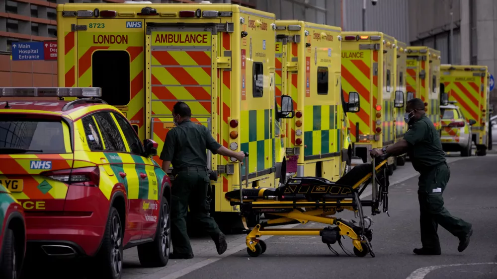 Paramedics push a trolley next to a line of ambulances outside the Royal London Hospital in the Whitechapel area of east London, Thursday, Jan. 6, 2022. Health authorities across the U.K. simplified COVID-19 testing requirements on Wednesday, a move designed to cut isolation times for many people and that may ease the staffing shortages that are hitting public services amid an omicron-fueled surge in coronavirus infections. A string of National Health Service local organizations have declared "critical incidents" in recent days amid staff shortages. (AP Photo/Matt Dunham)