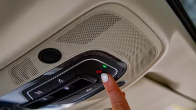 female driver's finger presses sos button on the ceiling panel of a modern car / Foto: Maria Argutinskaya