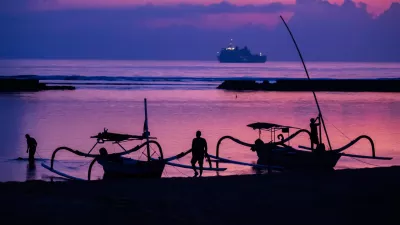 FILED - 14 November 2022, Indonesia, Nusa Dua: Men attach boats to the beach of Nusa Dua before sunrise on the day before the start of the G20 summit, with an Indonesian Navy ship visible in the background. Starting next year, tourists entering the Indonesian resort island of Bali will have to pay a fee of ten US dollars (nine euros) per person. Photo: Christoph Soeder/dpa
