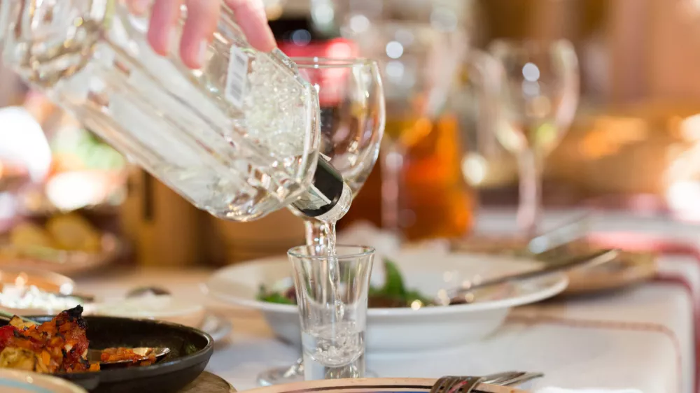 Feast in a restaurant, pouring vodka into the glass closeup