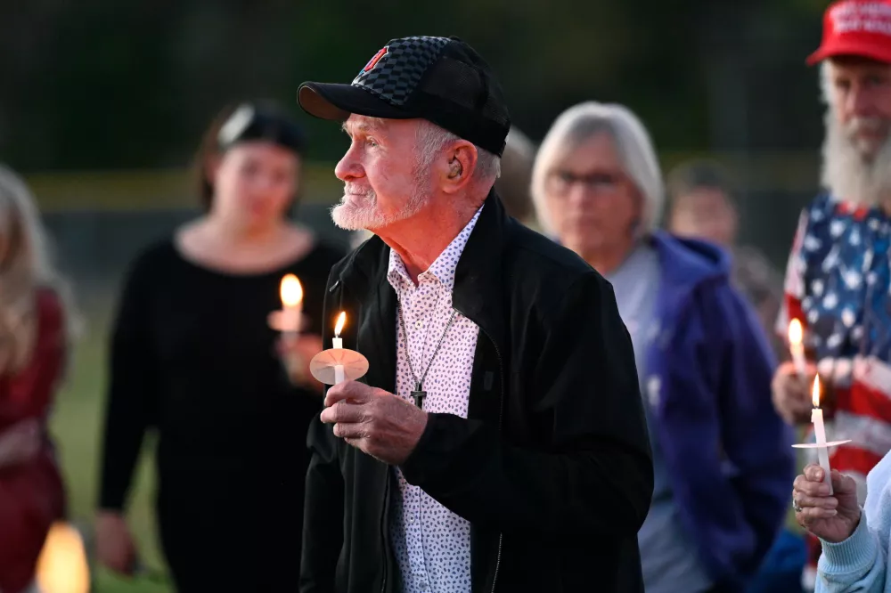 Attendees hold their lit candles during a vigil after a nearby church shooting held at Holy Redeemer Church in Burton, Mich., Sunday, Sept. 28, 2025. (AP Photo/Jose Juarez)