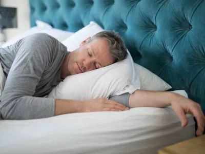 Man sleeping on bed in bedroom at home
