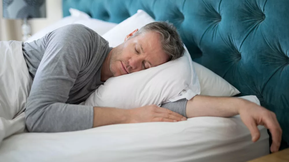 Man sleeping on bed in bedroom at home