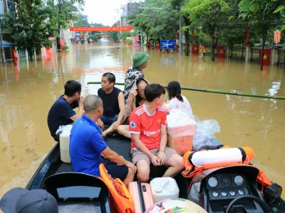 People move by a boat in a flooded street caused by rain following typhoon Bualoi in Lao Cai, Vietnam, Tuesday, Sept. 30, 2025. (Do Tuan Anh/VNA via AP)
