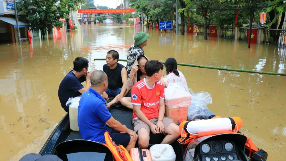 People move by a boat in a flooded street caused by rain following typhoon Bualoi in Lao Cai, Vietnam, Tuesday, Sept. 30, 2025. (Do Tuan Anh/VNA via AP)