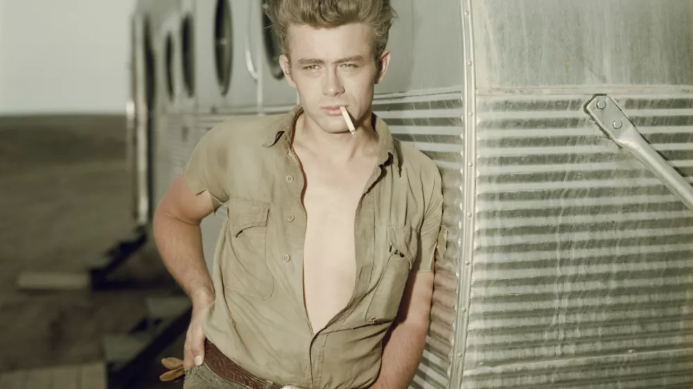 circa 1955: American actor James Dean (1931 - 1955) leaning against a dressing room trailer with his shirt open to the waist while smoking a cigarette on the set of director George Stevens's film, 'Giant,' in which he starred. (Photo by Hulton Archive/Getty Images) / Foto: Hulton Archive