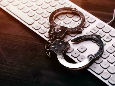 2TDENA2 High tech IT cyber crime arrest concept, image of police handcuffs over computer keyboard, selective focus