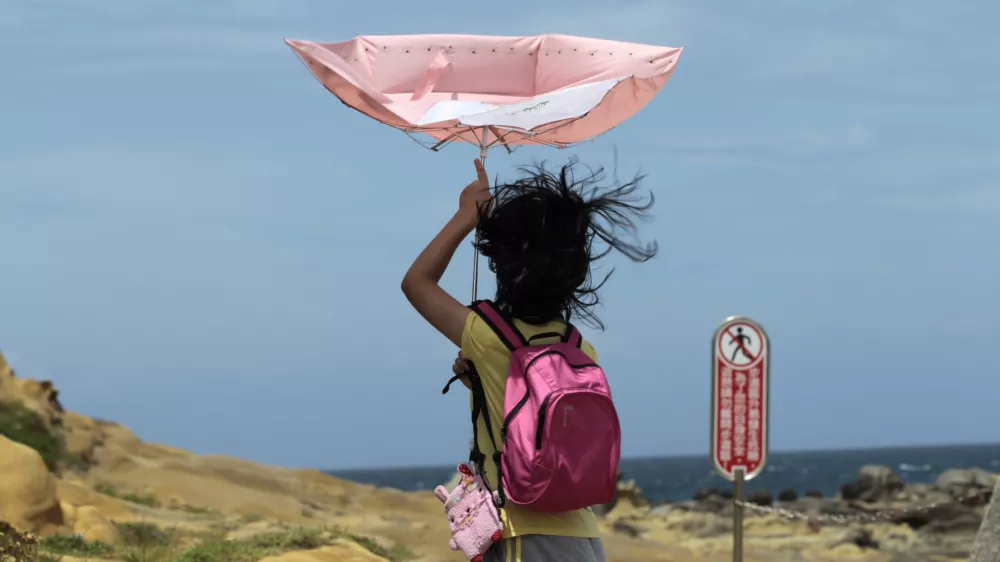A girl struggles with winds from approaching Typhoon Matmo along the eastern coast of Keelung, northeastern Taiwan, Tuesday, July 22, 2014. The eye of Typhoon Matmo is expected to make landfall in eastern Taiwan early Wednesday bringing heavy rain and winds with gusts over 130 kilometers (85 miles) per hour. (AP Photo/Wally Santana)