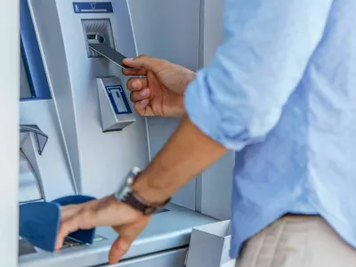 Man using a street ATM machine and withdrawing money, close up photo