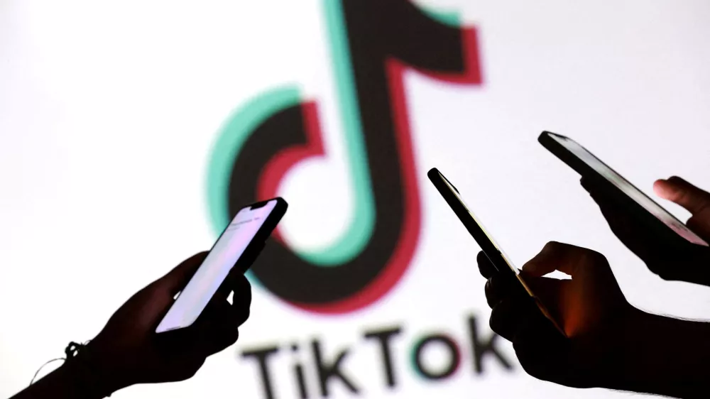 FILE PHOTO: Teenagers pose for a photo while holding smartphones in front of a TikTok logo in this illustration taken September 11, 2025. REUTERS/Dado Ruvic/Illustration/File Photo