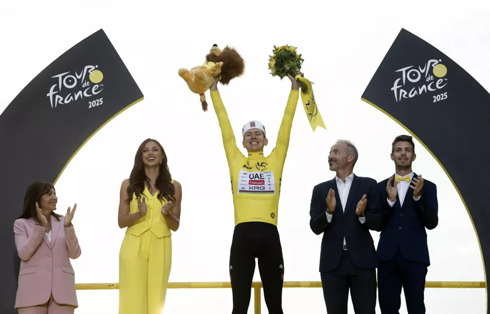 Cycling - Tour de France - Stage 21 - Mantes-la-Ville to Paris - Paris, France - July 27, 2025 UAE Team Emirates XRG's Tadej Pogacar celebrates on the podium wearing the yellow jersey after winning the Tour de France, as Paris' mayor Anne Hidalgo applauds REUTERS/Benoit Tessier