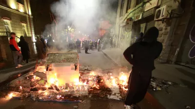 A demonstrator stands behind a burning barricade not far from a police line during an opposition rally in the city center of Tbilisi, Georgia, on Sunday, Oct. 5, 2025, boycotting the municipal elections and calling for the release of political opponents. (AP Photo/Zurab Tsertsvadze)