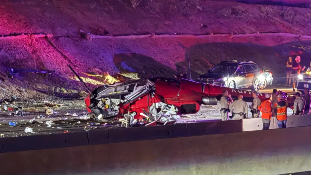 Law enforcement officers stand near the wreckage of a helicopter that crashed on eastbound Highway 50 in Sacramento, Calif., Monday, Oct. 6, 2025. (Robert Petersen via AP)