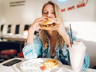 Young woman eating burger in restaurant