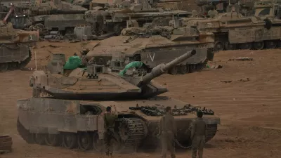 Israeli soldiers work on a tank near the Israeli-Gaza border, as seen from southern Israel, Thursday, Oct. 9, 2025, following the announcement that Israel and Hamas have agreed to the first phase of a peace plan to pause the fighting. (AP Photo/Ariel Schalit)
