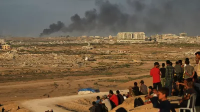 Displaced Palestinians watch smoke rise after Israeli military strikes as they gather on the coastal road near Wadi Gaza, in the central Gaza Strip, Thursday, Oct. 9, 2025. (AP Photo/Abdel Kareem Hana)