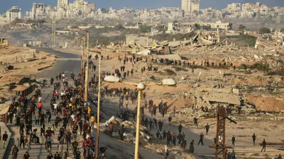 Israeli tanks are positioned on the coastal road leading to Gaza City as displaced Palestinians gather near Wadi Gaza in the central Gaza Strip, Thursday, Oct. 9, 2025. (AP Photo/Abdel Kareem Hana)