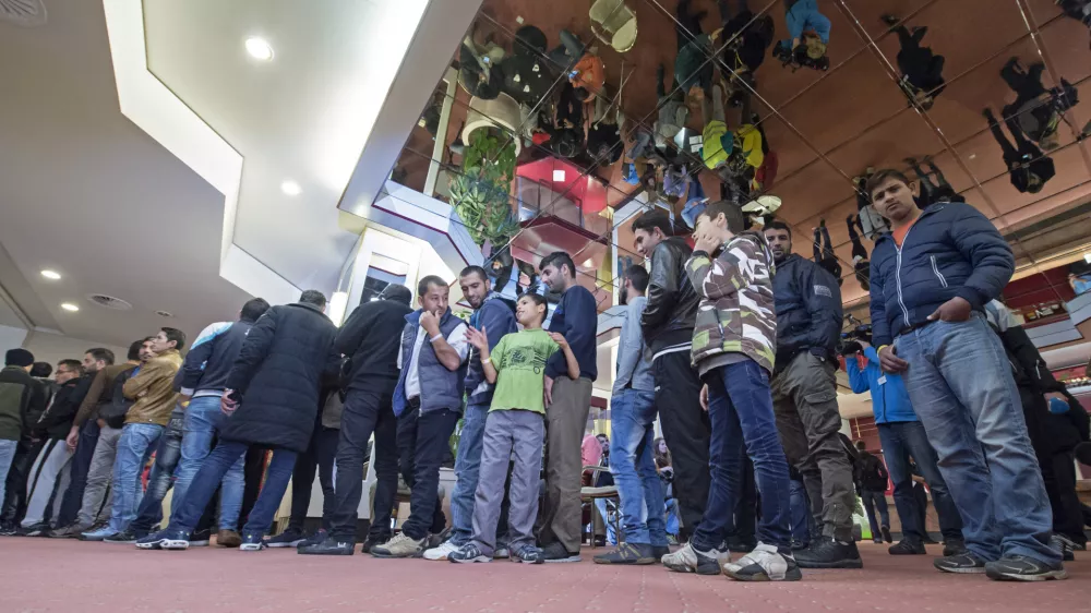 People line up for their meal in the initial reception center for asylum seekers in Halle/Saale, Germany, Friday, Oct. 16, 2015. The center in a former hotel has capacity for around 700 refugees. (AP Photo/Jens Meyer)