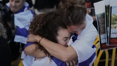 People hug in anticipation of the release of Israeli hostages held in Gaza during a gathering at a plaza known as hostages square in Tel Aviv, Israel, Monday, Oct. 13, 2025. (AP Photo/Oded Balilty)