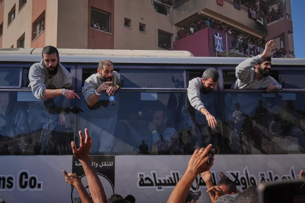 People greet freed Palestinian prisoners arriving on buses in the Gaza Strip after their release from Israeli jails under a ceasefire agreement between Hamas and Israel, outside Nasser Hospital in Khan Younis, southern Gaza Strip, Monday, Oct. 13, 2025. (AP Photo/Abdel Kareem Hana)