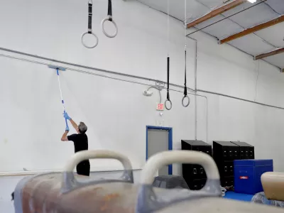 Southwest Gymnastics Training Center owner Brock Anstine cleans walls in his gym Monday, March 23, 2020, in Tempe, Ariz. Anstine, in compliance with CDC guidelines to help slow the spread of the COVID-19 coronavirus, has closed his gym and is paying his staff to deep cleans and paint the facility during their shut down. (AP Photo/Matt York)