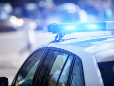 Police car with blue lights on the crime scene in traffic urban environment.