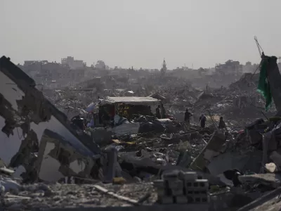 Palestinians walk among destroyed buildings in Gaza City, Thursday, Oct. 16, 2025. (AP Photo/Jehad Alshrafi)