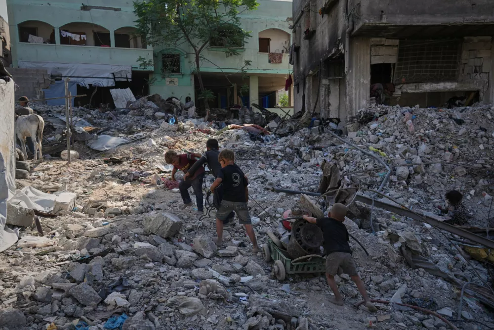 Palestinian children walk among destroyed buildings in Gaza City, Thursday, Oct. 16, 2025. (AP Photo/Jehad Alshrafi)