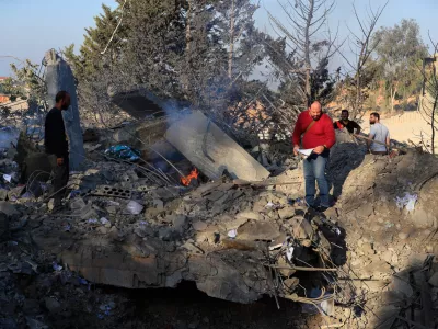 People look at the site of an Israeli airstrike on a cement plant in the southern Lebanese village of Ansar, Lebanon, Friday, Oct. 17, 2025. (AP Photo/Mohammad Zaatari)