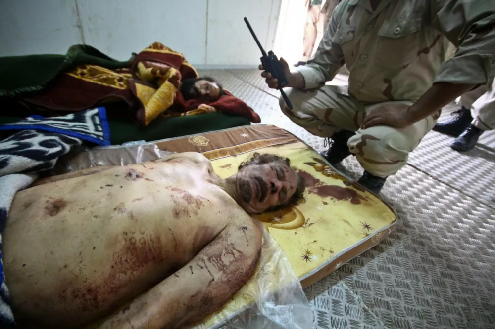 (111022) -- MISRATA, Oct. 22, 2011 -- A soldier of Libya's ruling National Transitional Council (NTC) squat near the bodies of Libya's fallen leader Muammar Gaddafi and his son Mutassim inside a storage freezer in Misrata, western Libya, on Oct. 22, 2011.,Image: 105436231, License: Rights-managed, Restrictions: WORLDWIDE RIGHTS AVAILABLE EXCLUDING CHINA, HONG KONG & FRANCE ONLY. End users shall not licence, sell, transmit, or otherwise distribute any photographs represented by eyevine, to any third party. Contact eyevine for more information: Tel: +44 (0) 20 8709, Model Release: no