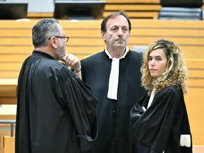 17 October 2025, France, Albi: Defendant's lawyers Alexandre Martin (C) and Emmanuelle Franck (R) wait for the opening of their client's trial for the murder of his wife in the courtroom of the Tarn Assize Courthouse. In a trial without a body, witnesses, or confession, a court in France has sentenced a man to 30 years in prison for the murder of his wife. Photo: Lionel Bonaventure/AFP/dpa