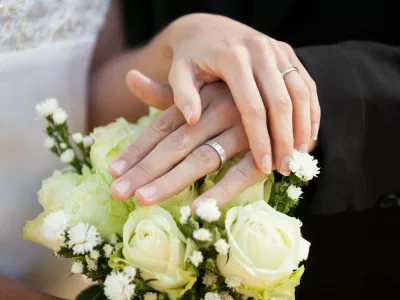 Close-up mid section of a newlywed couple with wedding rings and bouquet,Image: 187824776, License: Royalty-free, Restrictions:, Model Release: yes