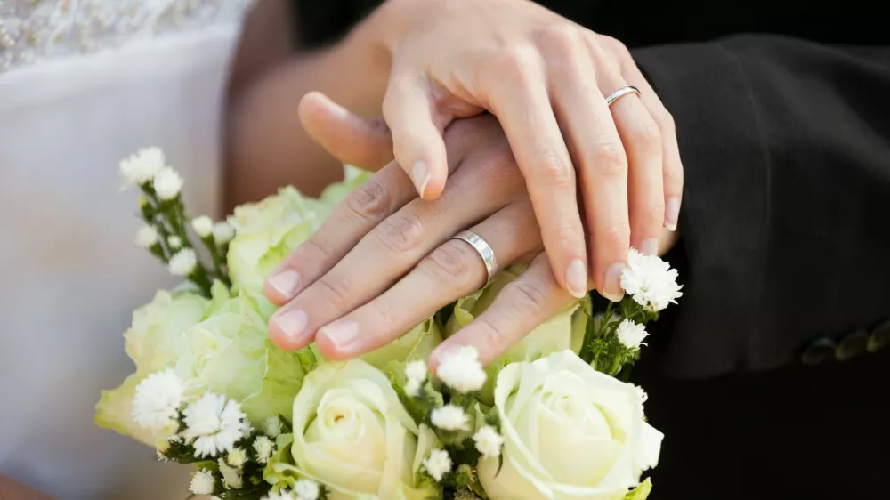 Close-up mid section of a newlywed couple with wedding rings and bouquet,Image: 187824776, License: Royalty-free, Restrictions:, Model Release: yes