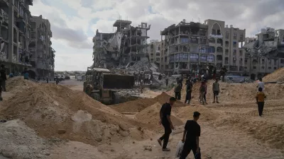 Palestinians watch members of the Hamas militant group searching for bodies of the hostages in an area in Hamad City, Khan Younis, in the southern Gaza Strip, Saturday, Oct. 18, 2025. (AP Photo/Jehad Alshrafi)