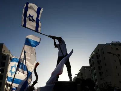 A man waves an Israeli flag as family and supporters gather on the day former Israeli hostage Elkana Bohbot returns home after leaving the hospital, following his release from captivity in Gaza, in Mevaseret Zion, Israel, October 19, 2025. REUTERS/Ronen Zvulun