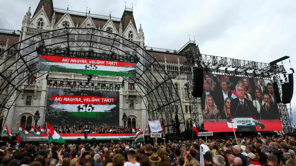 A text reading "Those who are Hungarian are coming with us" is displayed in the background as Hungarian Prime Minister Viktor Orban delivers a speech to mark the 69th anniversary of the Hungarian Uprising of 1956, in Budapest, Hungary, October 23, 2025. REUTERS/Bernadett Szabo