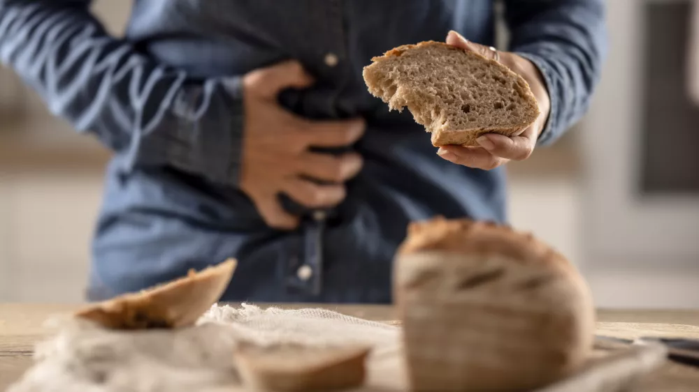 Woman can't eat bread and grain products because of gluten intolerance. A young celiac woman suffers from abdominal pain after eating fresh bread. / Foto: Marianvejcik