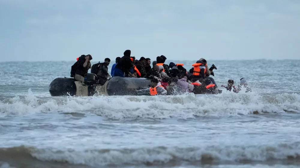 22 October 2025, France, Gravelines: People thought to be migrants wade through the sea to board a small boat in Gravelines. Photo: Gareth Fuller/PA Wire/dpa