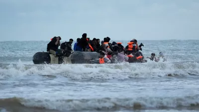 22 October 2025, France, Gravelines: People thought to be migrants wade through the sea to board a small boat in Gravelines. Photo: Gareth Fuller/PA Wire/dpa
