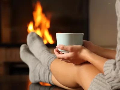 Woman with socks holding coffee in a fireplace / Foto: Antonioguillem