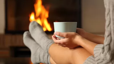 Woman with socks holding coffee in a fireplace / Foto: Antonioguillem