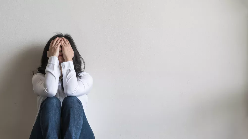 Anxiety disorder menopause woman, stressful depressed emotional person with mental health illness, headache and migraine sitting feeling bad sadly with back against wall on the floor in domestic home / Foto: Chinnapong