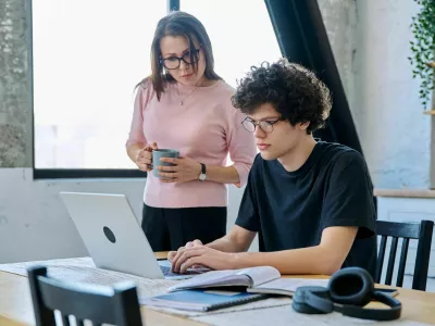Middle aged mother and son university student, together at home in the kitchen, serious guy and woman talking looking at computer laptop. Communication, relationship, lifestyle, family concept / Foto: Valeriy_g