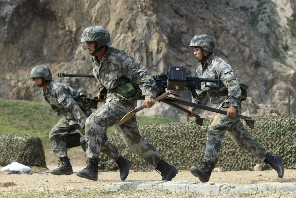 Members of People's Liberation Army (PLA) coastal defence force carry a machine gun during a drill to mark the upcoming 87th Army Day at a military base in Qingdao, Shandong province July 29, 2014. The PLA Army Day falls on August 1 every year. Chinese President Xi Jinping has pledged to strike hard against graft in the military, urging soldiers to banish corrupt practices and ensure their loyalty to the ruling Communist Party, state media reported on Friday. Picture taken July 29, 2014. REUTERS/Stringer (CHINA - Tags: MILITARY POLITICS ANNIVERSARY) CHINA OUT. NO COMMERCIAL OR EDITORIAL SALES IN CHINA / Foto: China Stringer Network