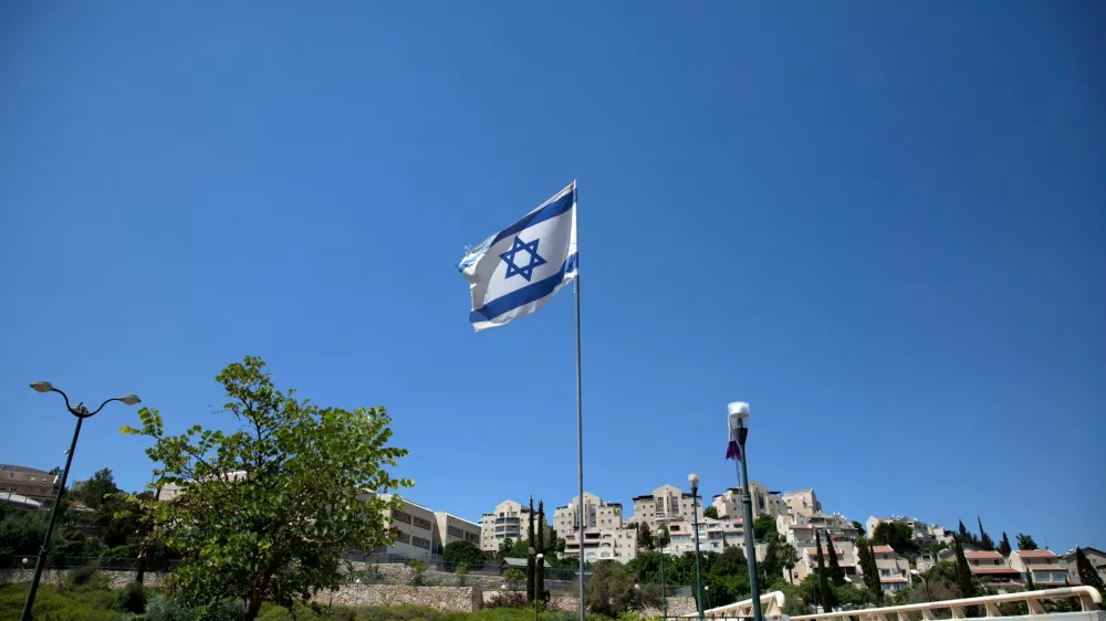 FILE PHOTO: The Israeli national flag flutters as apartments are seen in the background in the Israeli settlement of Maale Adumim in the Israeli-occupied West Bank August 16, 2020. Picture taken August 16, 2020. REUTERS/Ronen Zvulun/File Photo