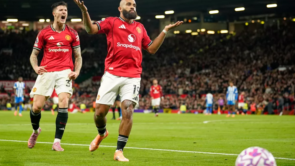 Manchester United's Bryan Mbeumo, front, celebrates with Benjamin Sesko after scoring his side's third goal during the English Premier League soccer match between Manchester United and Brighton & Hove Albion in Manchester, England, Saturday, Oct. 25, 2025. (AP Photo/Dave Thompson)