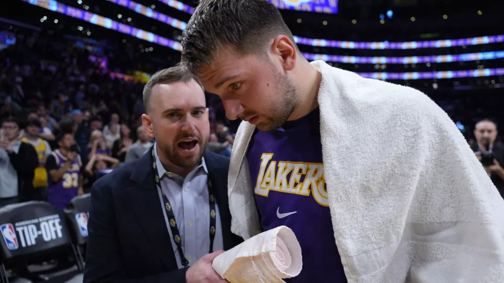 Oct 24, 2025; Los Angeles, California, USA; Los Angeles Lakers communications director Mitch Heckart (left) talks with guard Luka Doncic (77) after the game against the Minnesota Timberwolves at Crypto.com Arena. Mandatory Credit: Kirby Lee-Imagn Images