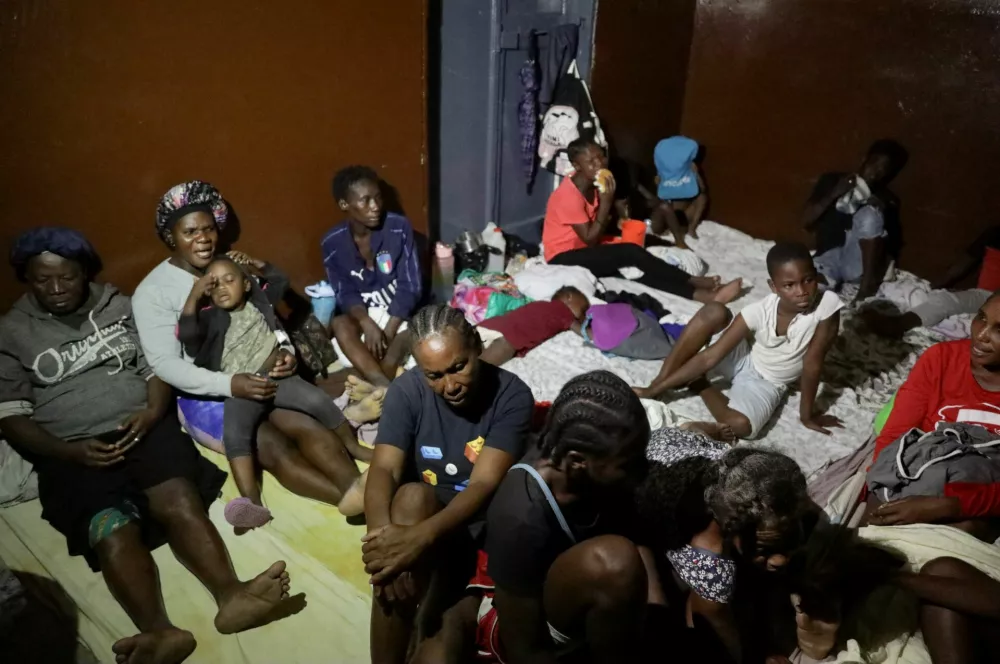 People gather at a school turned shelter while Haiti is seeing downpours from the outer bands of Hurricane Melissa, as the storm is churning towards Cuba, after making landfall in Jamaica, in Les Cayes, Haiti, October 28, 2025. REUTERS/Patrice Noel