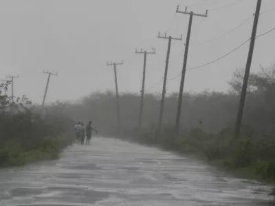 People walk along a road during the passing of Hurricane Melissa in Rocky Point, Jamaica, Tuesday, Oct. 28, 2025. (AP Photo/Matias Delacroix)