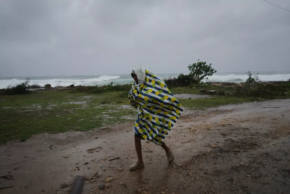 A man walks under the rain before the arrival of Hurricane Melissa in Canizo, a village in Santiago de Cuba, Monday, Oct. 28, 2025. (AP Photo/Ram&oacute;n Espinosa)